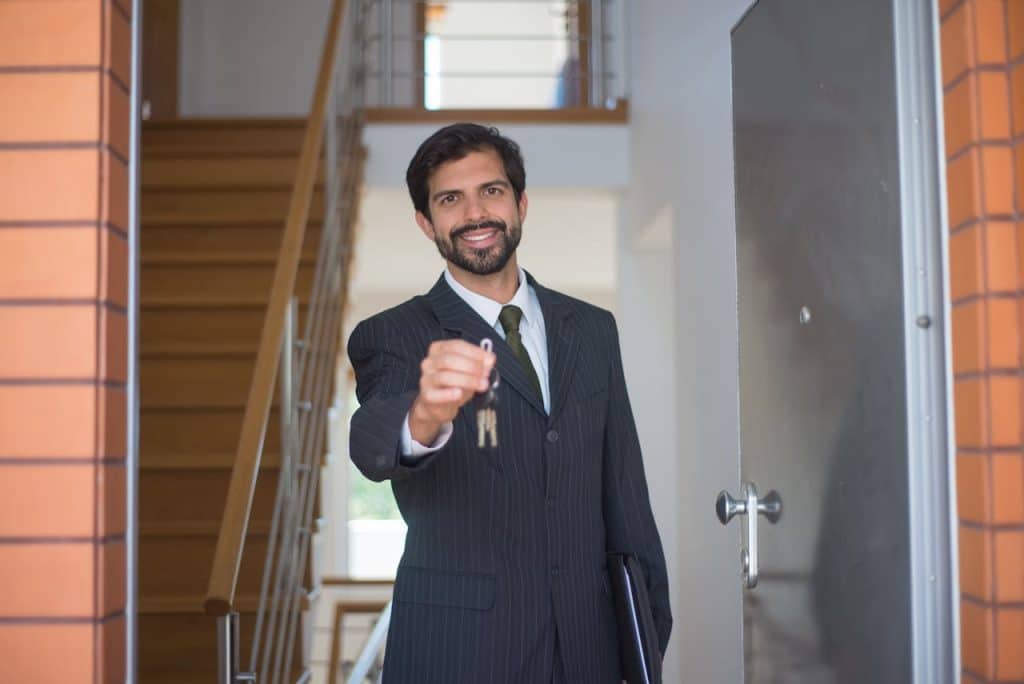 A professional real estate agent handing over keys to a new homeowner.