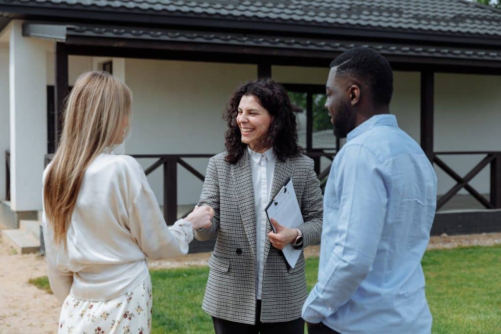 A real estate agent meeting with clients outdoors, discussing property options.