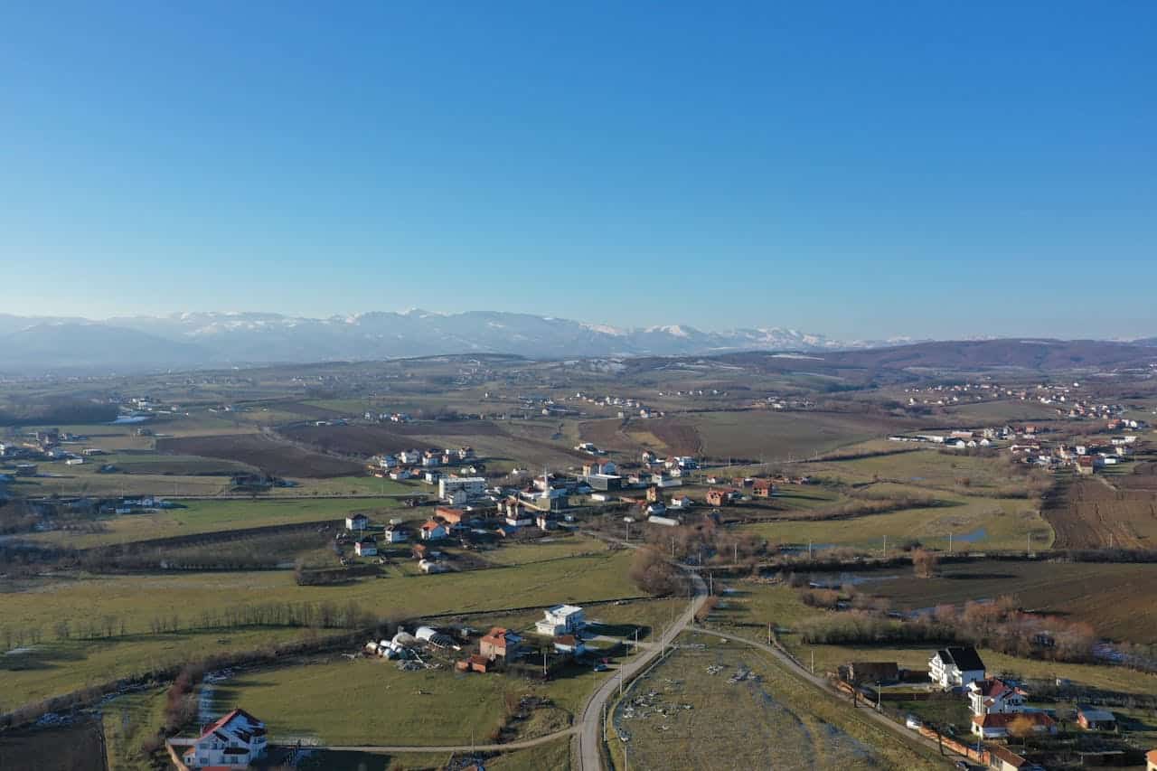 Aerial view of a scenic village landscape with mountains in the background.