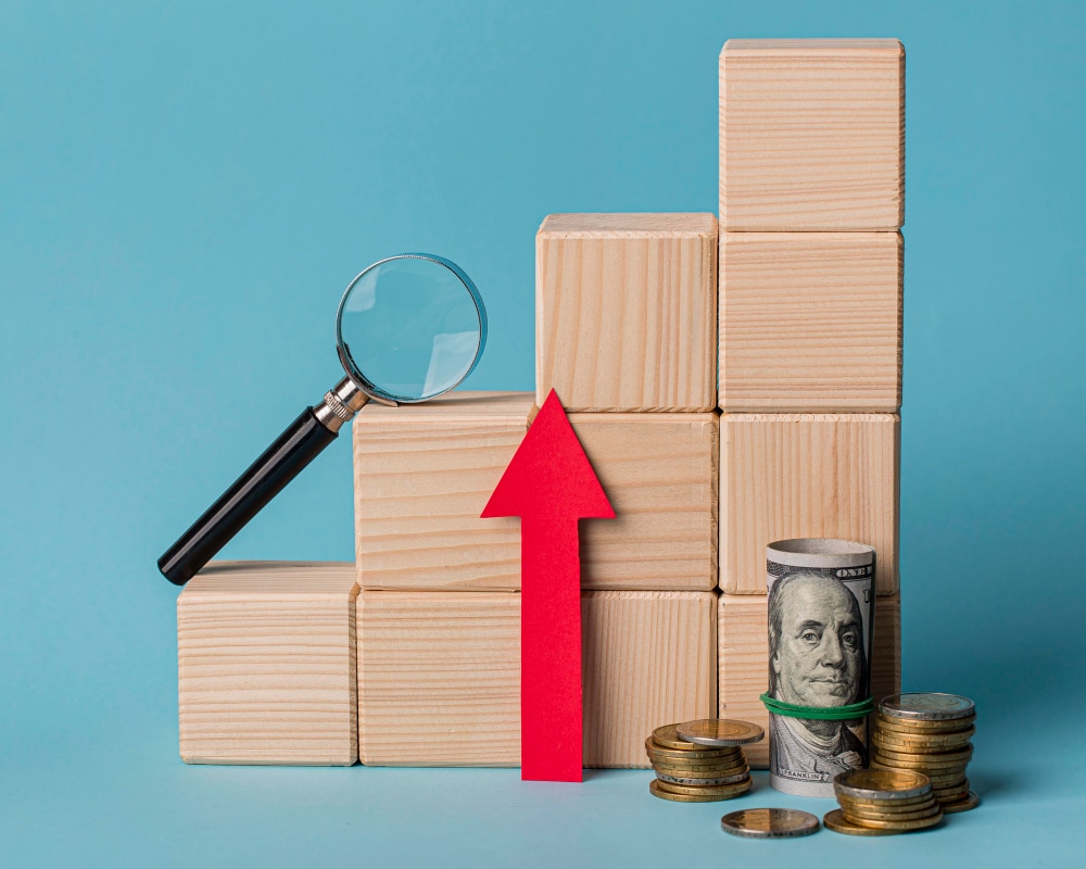 wooden blocks representing financial growth with a magnifying glass and money
