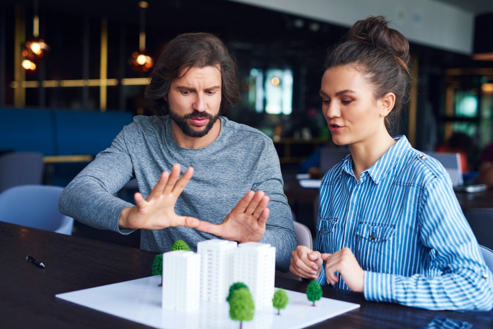 Two professionals discussing an architectural model in a modern workspace.