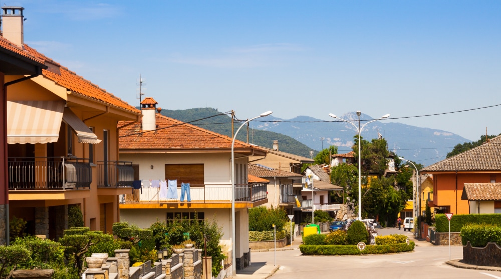 A peaceful village street lined with houses and mountains in the background.