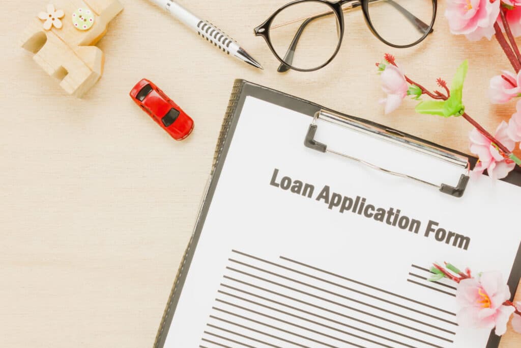 Overview of a loan application form with decorative items and a red toy car.