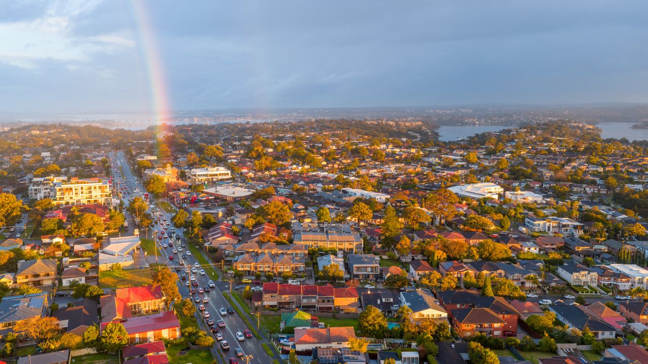 Aerial view of a vibrant cityscape with houses and a rainbow in the background.