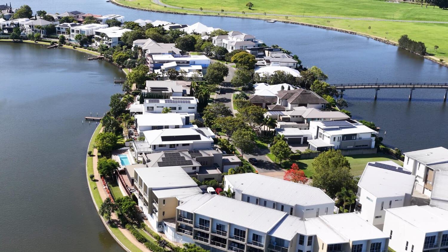 Aerial view of waterfront homes along a river with lush greenery.